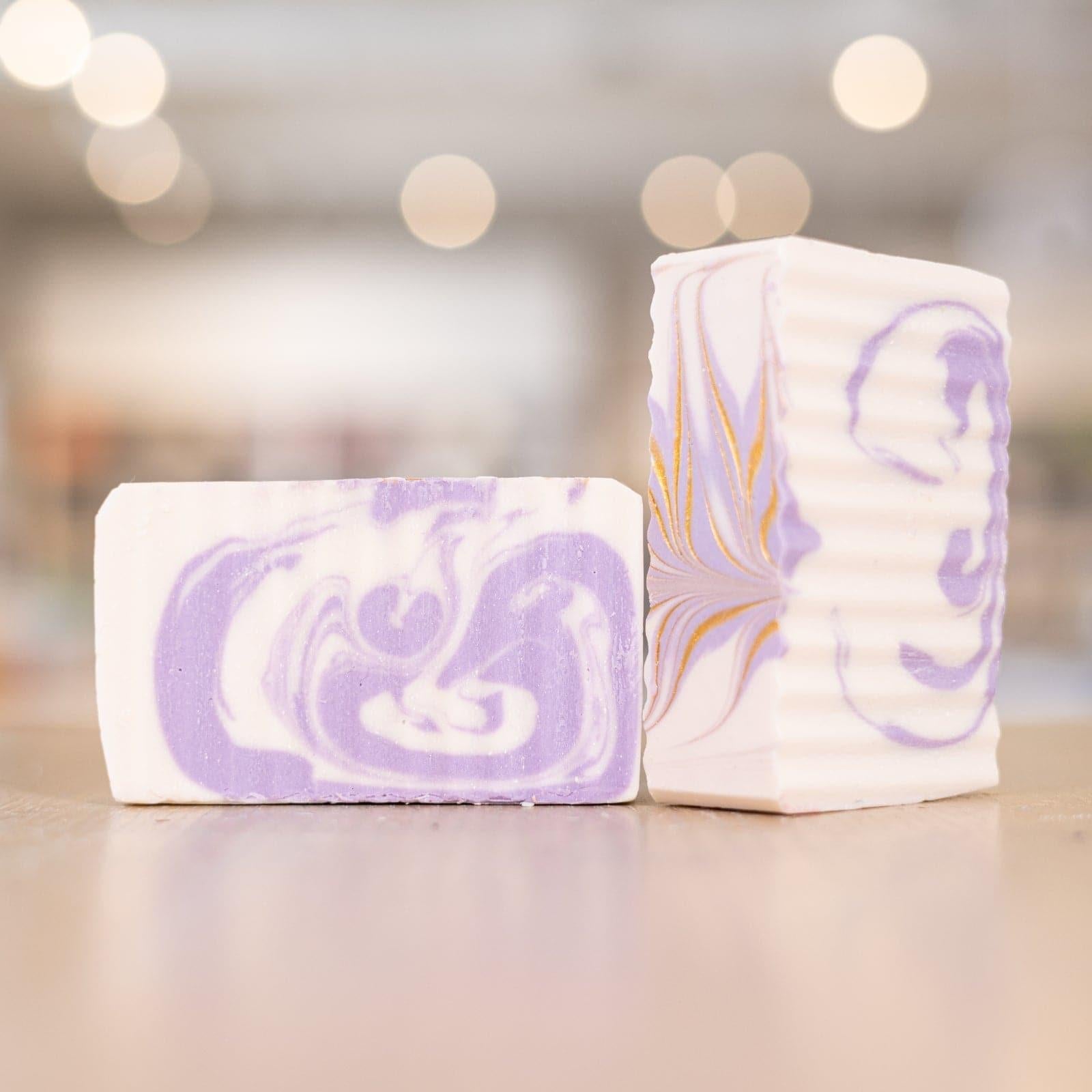 Two white and purple bars of Buff City Soap's lavender shea butter soap